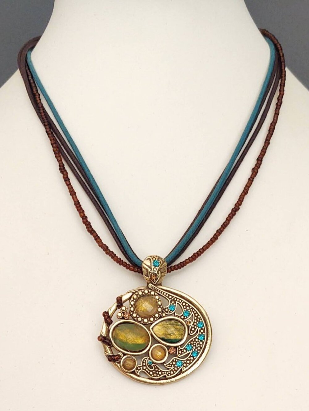 Gold tone pendant necklace with green and yellow beads and cz accents on cording